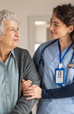 Young caregiver helping senior woman walking. Nurse assisting her old woman patient at nursing home. Senior woman with walking stick being helped by nurse at home. (Young caregiver helping senior woman walking. Nurse assisting her old woman patient at